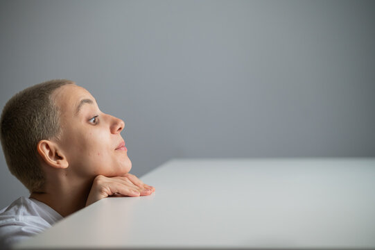 A Caucasian woman with short hair peeks out from under a table. 