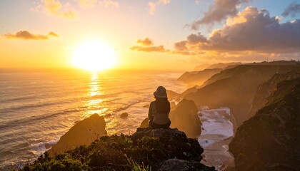 A solitary figure sits atop a cliff, gazing at the ocean during a golden sunset. Dramatic light bathes cliffs and waves