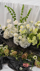 process of wedding decoration of the bride's table. Flower arrangement in white and green colors, vases with flowers, necklace. Rose, chrysanthemum, dahlia, grapes, hydrangea, anthurium, beargrass
