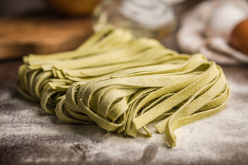 Green tagliatelle pasta on kitchen table.