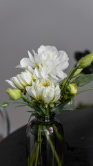 small decorative cute bouquet in a glass vase in white and green tones. Gypsophila, dahlia, eustoma, chrysanthemum