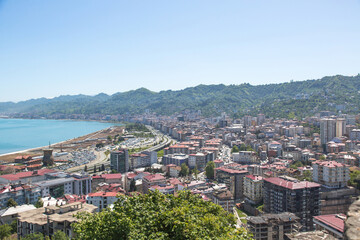 Obraz premium Panoramic view of Rize city on the Black Sea coast, Turkey, with modern buildings, green mountains, and blue sky, perfect for travel, tourism, and urban landscape concepts