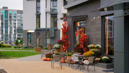 outdoor cafe vibrant autumn decor, urban setting with colorful plants and pumpkins. encourages cozy atmosphere for customers, enhancing city lifestyle with seasonal charm