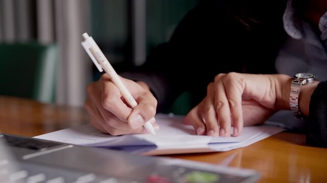 Professional woman in law firm writing legal notes from reference book with justice items around.