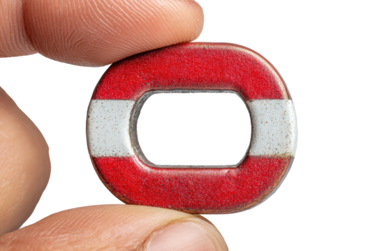 Close-up of a small, circular metal washer.  Red and white painted band.  Oval hole in the center. Held by fingers
