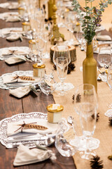 Elegant rustic wedding table decoration with golden bottle and crystal glasses;Close-up of a rustic chic wedding table setting with crystal glasses, golden bottle vases and beige napkins on a table.