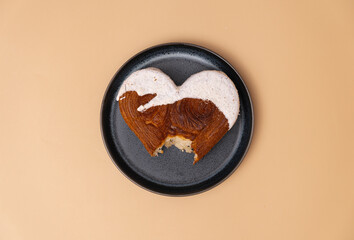 Bitten croissant on plate Valentine's Day holiday present Delightful and vibrant heartshaped pastry croissant treat, beautifully topped with colorful frosting galore. Copy space. Food experimentation