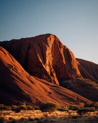 Desert mountain bathed in warm orange sunlight, atmospheric landscape capturing the grandeur and isolation of nature in a minimalist travel scene