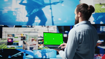 Casual young guy connecting on social platforms with mockup on pc, enjoying his online activity and interaction via social media. Engaging with people for entertainment. Camera B.