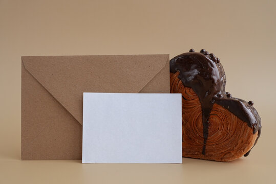 White paper note template greeting card mockup Delicious fresh croissant topped with Dark chocolate flavor Ganache. Creation unique heart shape bakery. Puff pastry holiday love gift present idea