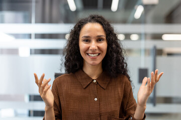 Young woman smiling at camera, having engaging conversation during online video conference,...