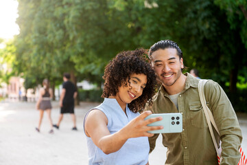 Interracial couple smiling taking selfie in park