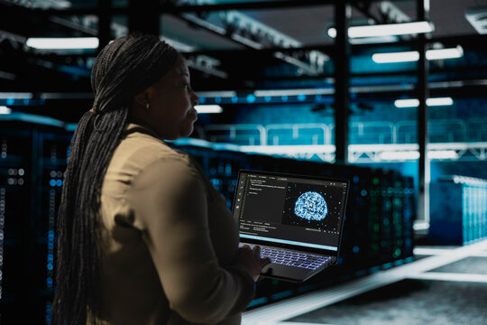 Data center programmer using AI neural network to test equipment used for hosting digital services. Server hub employee repairing mainframes managing file transfers using machine learning