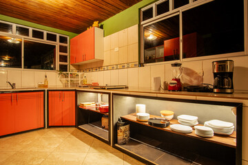 Cozy rustic kitchen with red cabinets, wooden ceiling, and soft lighting. A warm, inviting space combining functionality and handcrafted charm.