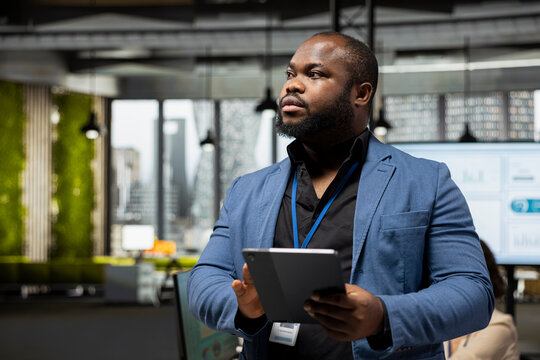 African american businessman overseeing analytics tasks with a tablet, using data and KPI metrics for business management and global expansion. Improve efficiency and productivity.