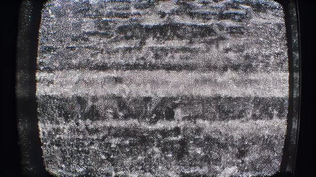 Close-up view of a television screen filled with static, displaying a pixelated, grainy texture