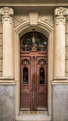 Obraz premium ornate wooden double door framed by stone columns and classical architectural details, front view of historic european building entrance