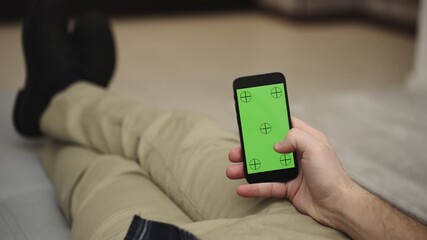 Young man resting and using mobile phone and doing swiping, scrolling gestures
