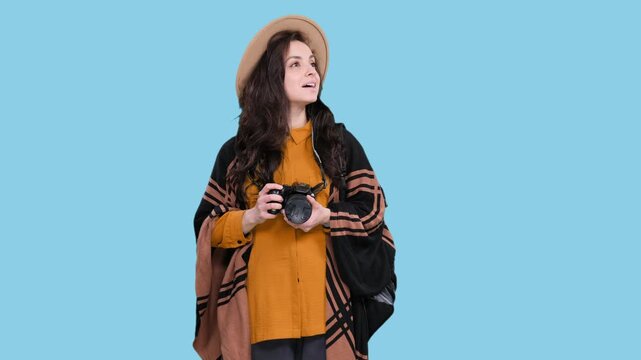 Smiling woman posing with camera and backpack on the blue chroma key