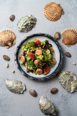 A vibrant seafood salad delights with shrimp, greens, and colorful fruits. Surrounding seashells add a coastal feel, evoking a seaside dining experience