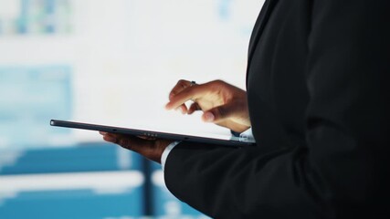 Close up of businesswoman using tablet to compare company KPIs data on digital videowall before making decisions. Entrepreneur analyzing key performance indicators using device app - Powered by Adobe