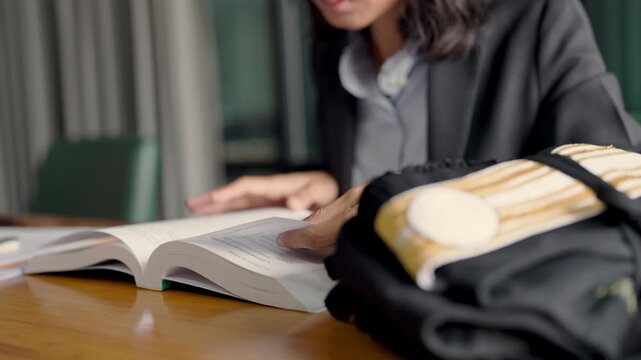 Female law student flipping pages of legal textbook with judge s robe on desk, symbol of legal education and career path.