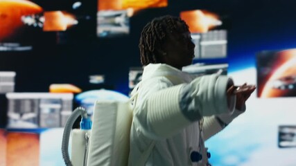 Cheerful astronaut dancing while monitoring mission data on displays. Jolly spacecraft cosmonaut having fun doing dance moves while looking at space travel multimedia digital backdrop, camera B