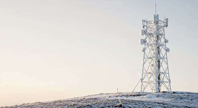 A towering telecommunications mast, covered in frost, stands on a snow-dusted hill under a bright, clear sky, symbolizing global connectivity and remote infrastructure.