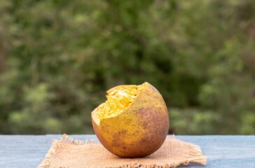 Closeup of Ripe Indian Bael Fruit Juice or Wood Apple Isolated on Wooden Background with Copy Space, Also Known as Aegle Marmelos, Bengal Quince, Japanese Bitter Orange