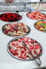 Snack bar cart with colorful and flavored candies and sweets, marshmallows, and fruit jellies for parties and events to serve in small cups.
