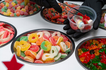 Snack bar cart with colorful and flavored candies and sweets, marshmallows, and fruit jellies for parties and events to serve in small cups.
