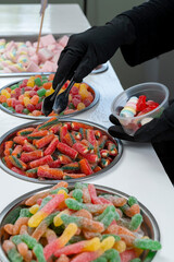Snack bar cart with colorful and flavored candies and sweets, marshmallows, and fruit jellies for parties and events to serve in small cups.
