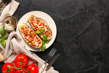 Stuffed eggplants with tomatoes, basil leaves and jug of oil on black grunge background
