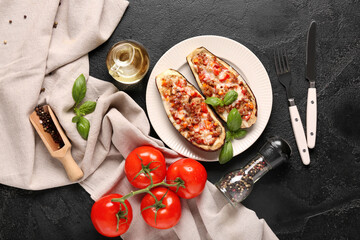 Stuffed eggplants with tomatoes, basil leaves and jug of oil on black grunge background