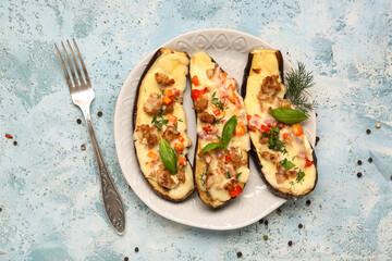 Plate with stuffed eggplants, dill, peppercorns and basil leaves on blue grunge background