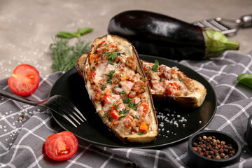 Plate with stuffed eggplants, tomato, dill and bowl of peppercorns on grey background