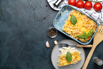 Baking dish and plate of pasta with basil leaves on blue grunge background