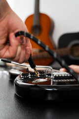 Jack cable is plugged into the black electric guitar, activating its signal path for rich tones and stage-ready sound. Plugging Cable into Electric Guitar close-up.