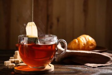 Cup of hot tea with sugar cubes on wooden background