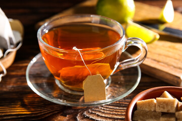 Cup of hot tea with sugar cubes on wooden background