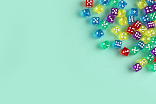 Many colorful game dices on turquoise background