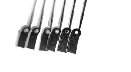 Close-up of several black metal rods or bars,  each with a small, rectangular tag affixed