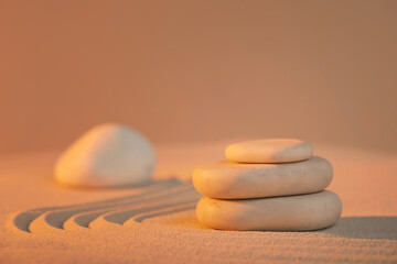 Stack of stones on light sand at sunset. Zen concept