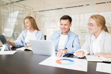 Obraz premium Business team collaborates in modern office space on project plans while using laptops and tablets for effective communication