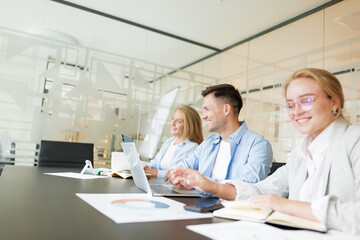 Obraz premium Team members collaborate in a modern office environment while discussing projects and reviewing data on laptops and charts
