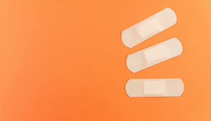 Adhesive bandages on orange background symbolizing healing and care