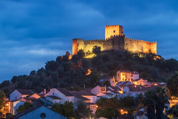 Belver, Portugal at dusk with the castle illuminated on top of the hill.
