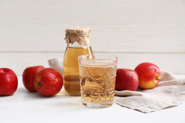 Fresh fruits with bottle and glass of apple cider on white wooden background