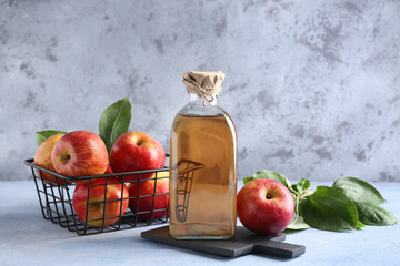 Fresh fruits with bottle of apple cider on grey grunge background
