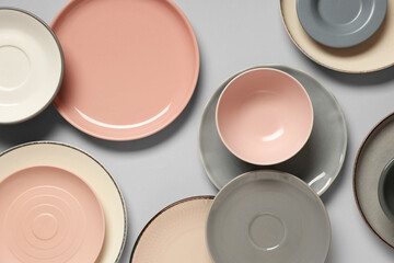 Set of clean plates and bowls on grey background